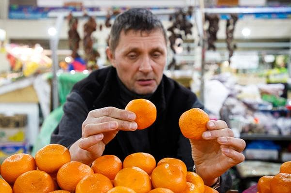 Чоловік обирає мандарини